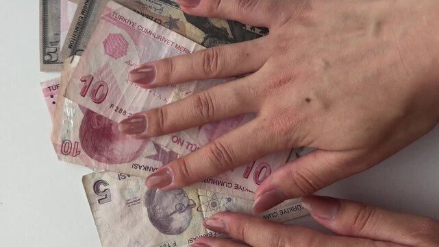 Woman's hands counting turkish lira and us dollar banknotes on a white background, demonstrating the concept of exchange rates, currency conversion, and global finance