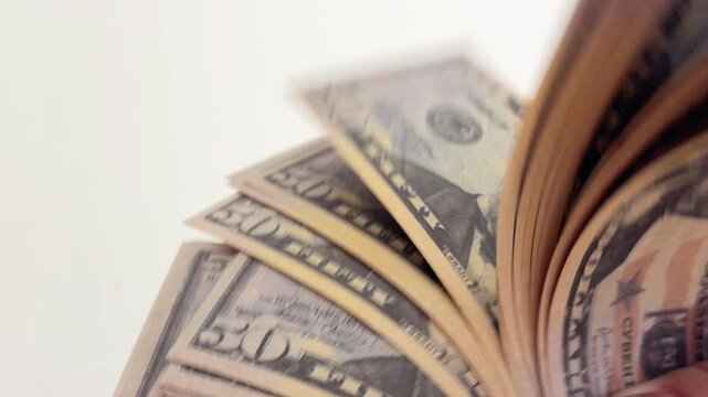 Close up of female hands with a polished manicure counting a thick fan of fifty dollar banknotes, symbolizing wealth, business success, financial independence, and earned income