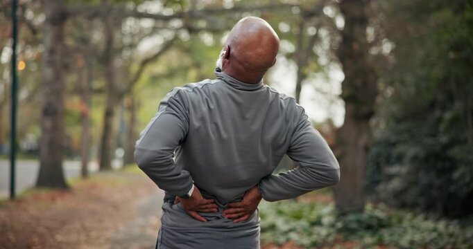 Fitness, man or stretching with back pain at park for poor runner form, weak core or sport injury. Earphones, mature black person or spine compression for cardio accident, incorrect technique or ache
