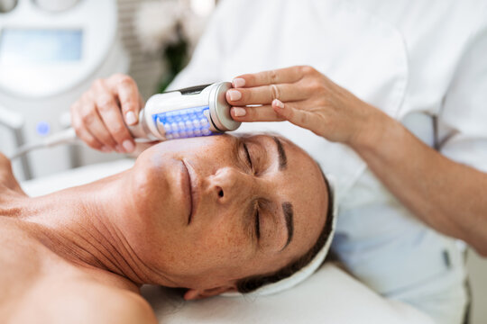 A professional aesthetician uses advanced beauty roller technology for skin tightening and body contouring on a relaxed client in a spa salon.