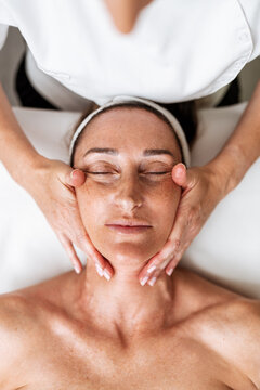 Receiving a soothing cosmetic therapy session with gentle acupressure and rejuvenating touch for complete physical relaxation and skin health.