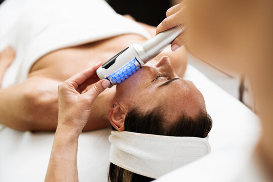 A professional aesthetician uses advanced beauty roller technology for skin tightening and body contouring on a relaxed client in a spa salon.