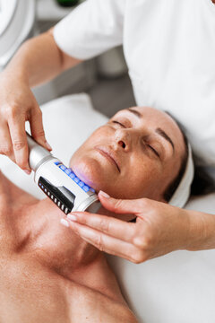 A professional aesthetician uses advanced beauty roller technology for skin tightening and body contouring on a relaxed client in a spa salon.