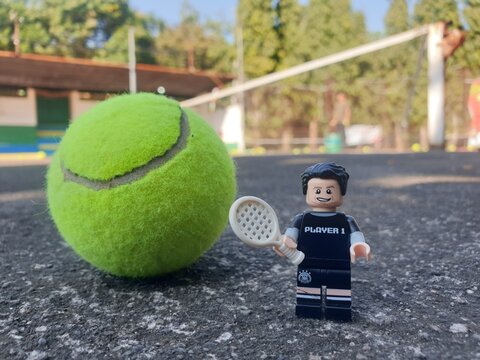 Indonesia - August 31, 2024 : Mini toy of action figure at tenniscourt with blurred background. Sport photography concept design. Miniature Young man athlete at tennis club.