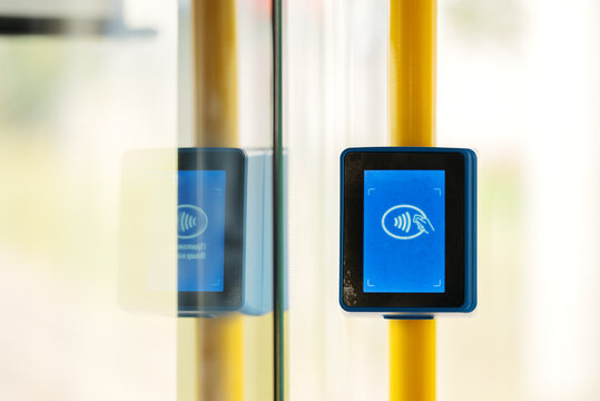 Contactless ticket validator terminal inside public transport. Electronic payment machine for credit cards and travel passes on city bus, train, or tram.