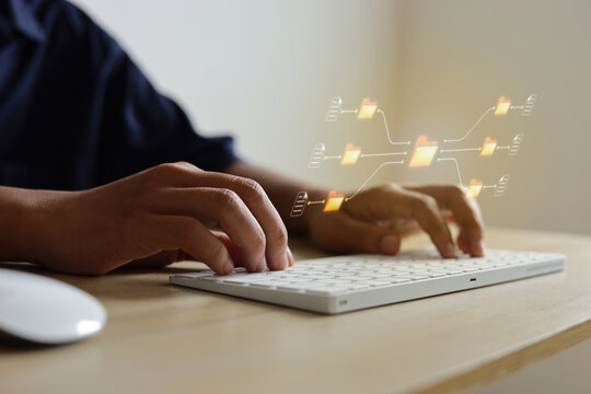 Close Up Of Hands Operating Keyboard At Desk With Digital Folders For Data Management