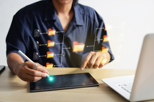 Person Using Digital Tablet For Business Organizing Data Folders Next To Laptop At Office