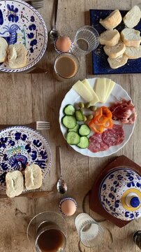 Breakfest table with bread, cheese, salami, olives and coffee zoom out