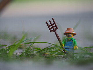 Obraz premium Indonesia - January 6, 2019 : Mini toy of action figure with blurred background. Toy photography concept. Farmer with harrow at green grass land conceptual design.