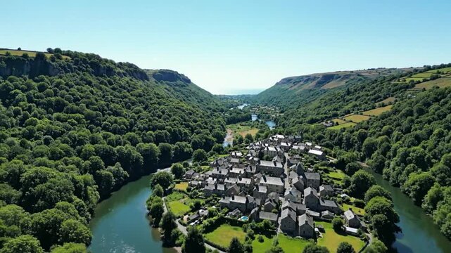 Aerial view of a picturesque village nestled in a lush valley with a winding river on a bright sunny day
