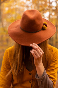 Fashionable redheaded young woman wearing felt hat in autumnal forest