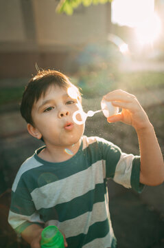 Boy blowing a soap bubble in the park during summer