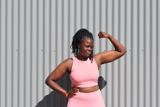 Young woman flexing biceps on sunny day