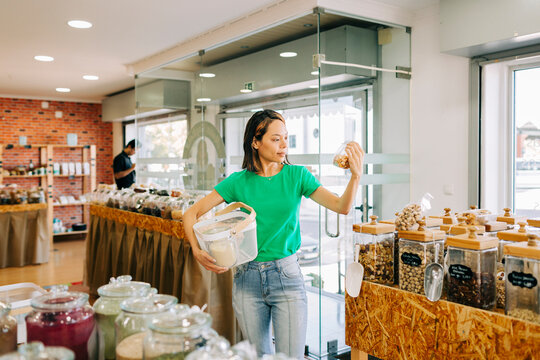Shopper holding glass jar in zero waste grocery store