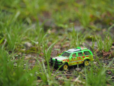 Indonesia - November 15, 2020 : Adventure, holiday and traveling conceptual design with mini toy. Blurred outdoor view. Unfocus stuff. Blurred green grass as a background. Conceptual photography.