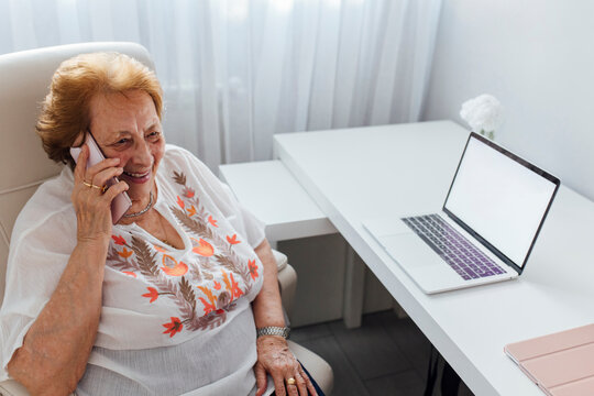 Happy woman talking on mobile phone at home
