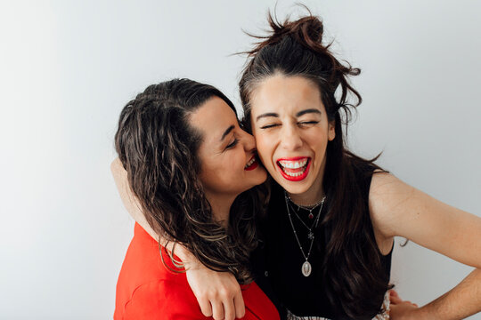 Happy bisexual couple enjoying in front of white wall
