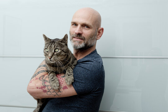 Tattooed man carrying his cat