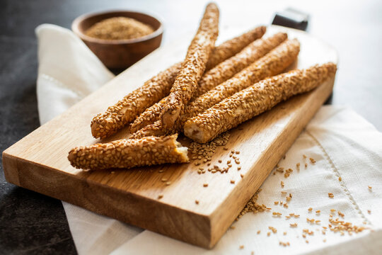 Cutting board and fresh Italian grissini breadsticks with sesame seeds
