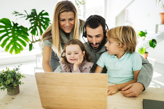 Smiling family on video call through laptop in living room