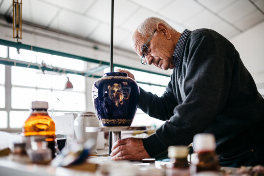Senior man decorating ceramic vase in his spare time