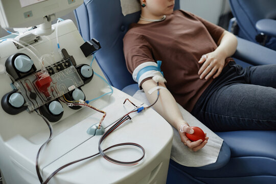Young woman lying on couch with ball in hand at blood donation center
