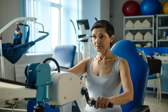 Female patient uses exercise machine during physiotherapy recovery