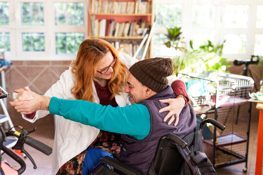 Female nurse motivating disabled man to getup from wheelchair at nursing home