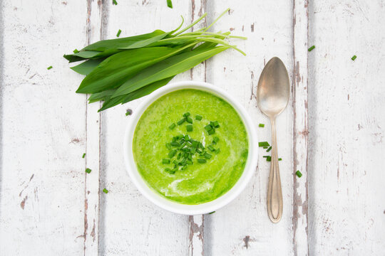 Bowl of ramson soup garnished with chives and cream