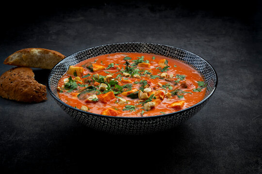 Vegetarian Indian halloumi korma curry with bread on dark background
