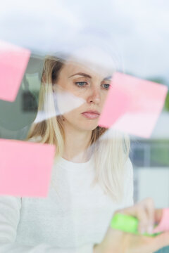 Female entrepreneur looking at adhesive note on office window