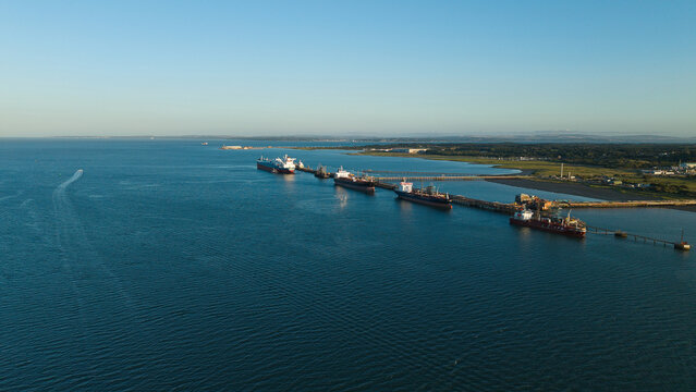 Aerial view of Fawley Refinery with large tankers docked at the industrial pier extending into the Solent in Southampton, England, United Kingdom.