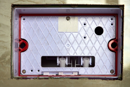 Close-up of concealed toilet flush installation mechanism inside tiled wall structure before final push button plate mounting, highlighting internal plumbing components