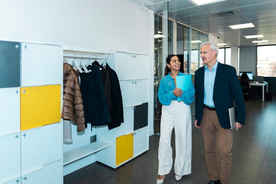 Businessman and businesswoman walk and discuss work in the office