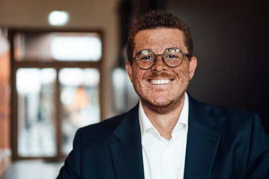Smiling man with freckles wears a suit in the office
