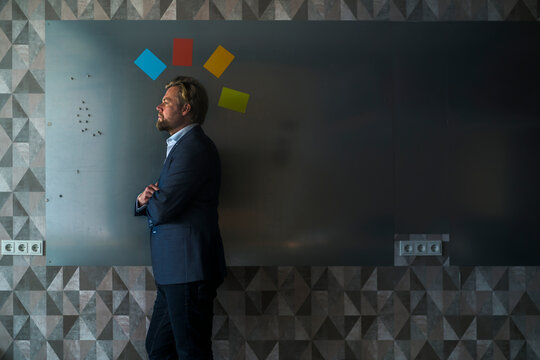 Businessman standing in front of magnet wall with mohican from colorful sticky notes