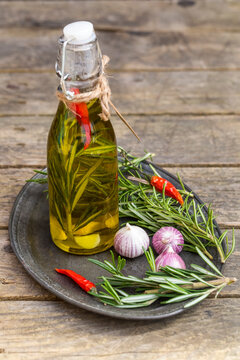 Rosemary oil in bottle, garlic, rosmary and chilli peppers on plate