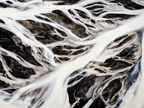 Glacial water of Hvita River flows across dark volcanic sediment