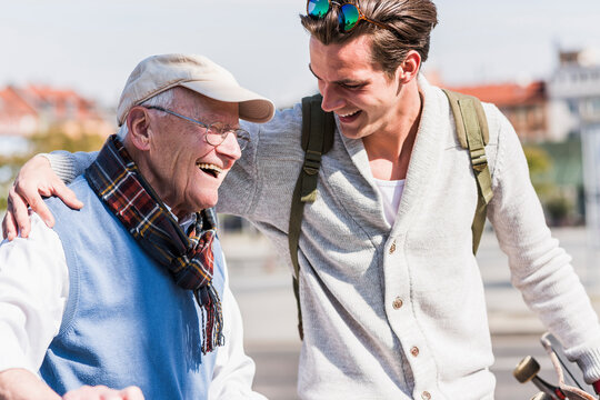 Happy senior man with adult grandson in the city on the move