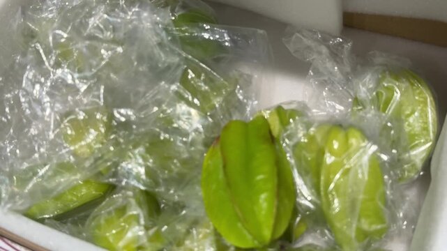 Fresh green carambola starfruit individually packed in clear plastic bags protects delicate tropical fruit while creating an attractive retail display for supermarkets and local markets. Close up.