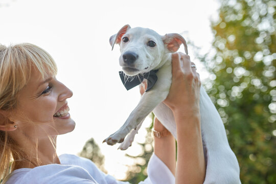 Happy woman holding dog wearing a bowtie outdoors