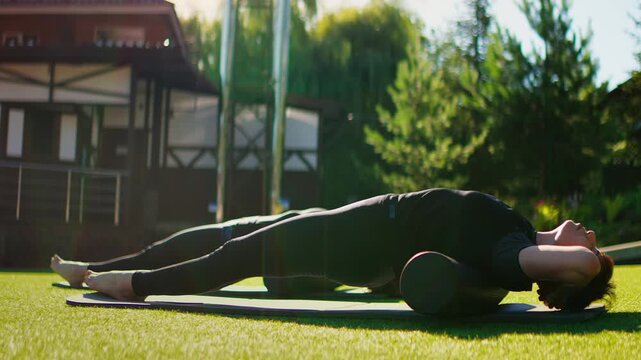 Elderly women practicing slow motion Pilates outdoors on yoga mats, focusing on core strength, balance, posture, and mindful stretching in a peaceful green setting