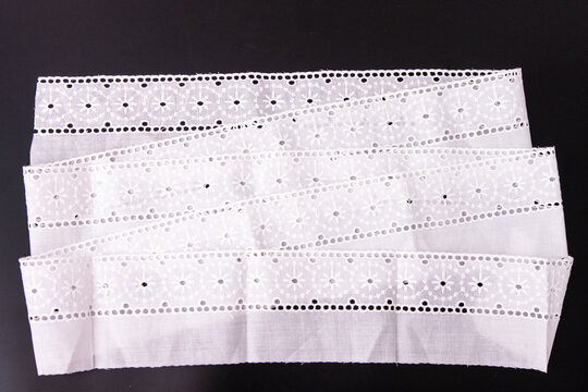 White floral lace ribbon trim, delicate cotton embroidery border fabric. Top view embroidered eyelet flower pattern.