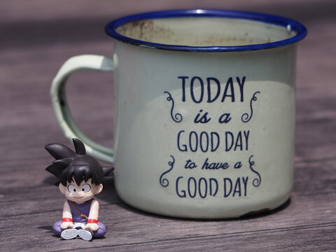 Indonesia - December 9, 2018 : Mini toy of action figure at outdoor with blurred background. Toy photography concept design. Minifigure of Songoku from Dragon Ball cartoon film with cup of drink.