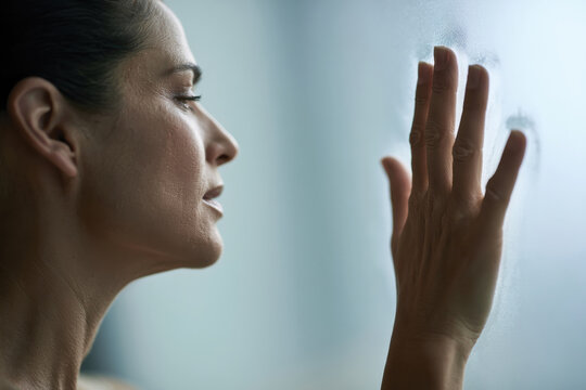 A woman gazes longingly through a fogged glass, encapsulating a moment of deep yearning and emotional connection, brilliantly reflecting the essence of human feeling.