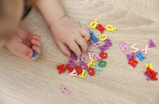 Baby hands play with many colorful letters on the table. Education, day of knowledge