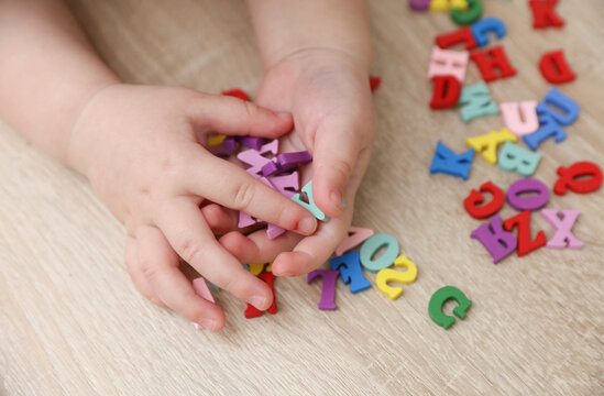Baby hands play with many colorful letters on the table. Education, day of knowledge