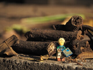 Fototapeta premium Indonesia - September 12, 2025 : Mini toy of action figure at table with blurred background. Miniature photography concept design. Minifigure of traveler man character with map and bag at outdoor.