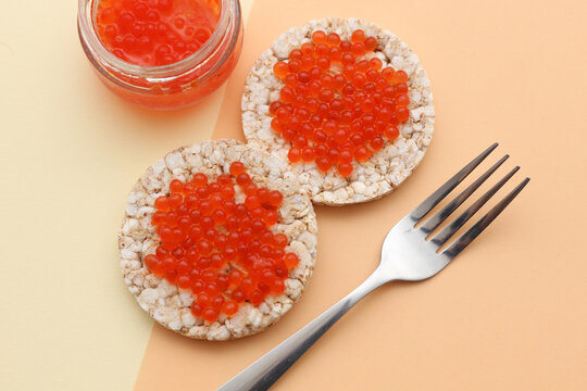 Rice round bread with red caviar and fork on beige background