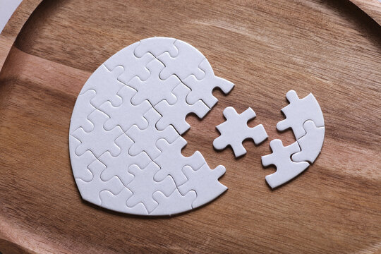 White blank heart-shaped puzzle on a wooden tray. Love, healthcare concept.